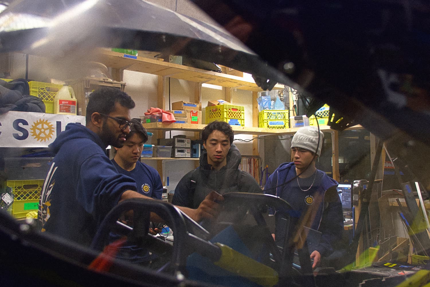 Martin and teammates in the UBC Solar bay on a motor installation night, seen through the car's canopy
